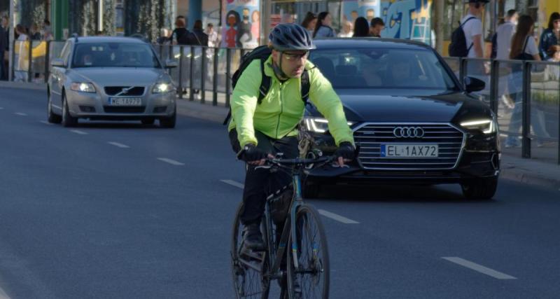  - Ce cycliste roule à contresens en ville, il slalome entre les voitures pour se frayer un chemin