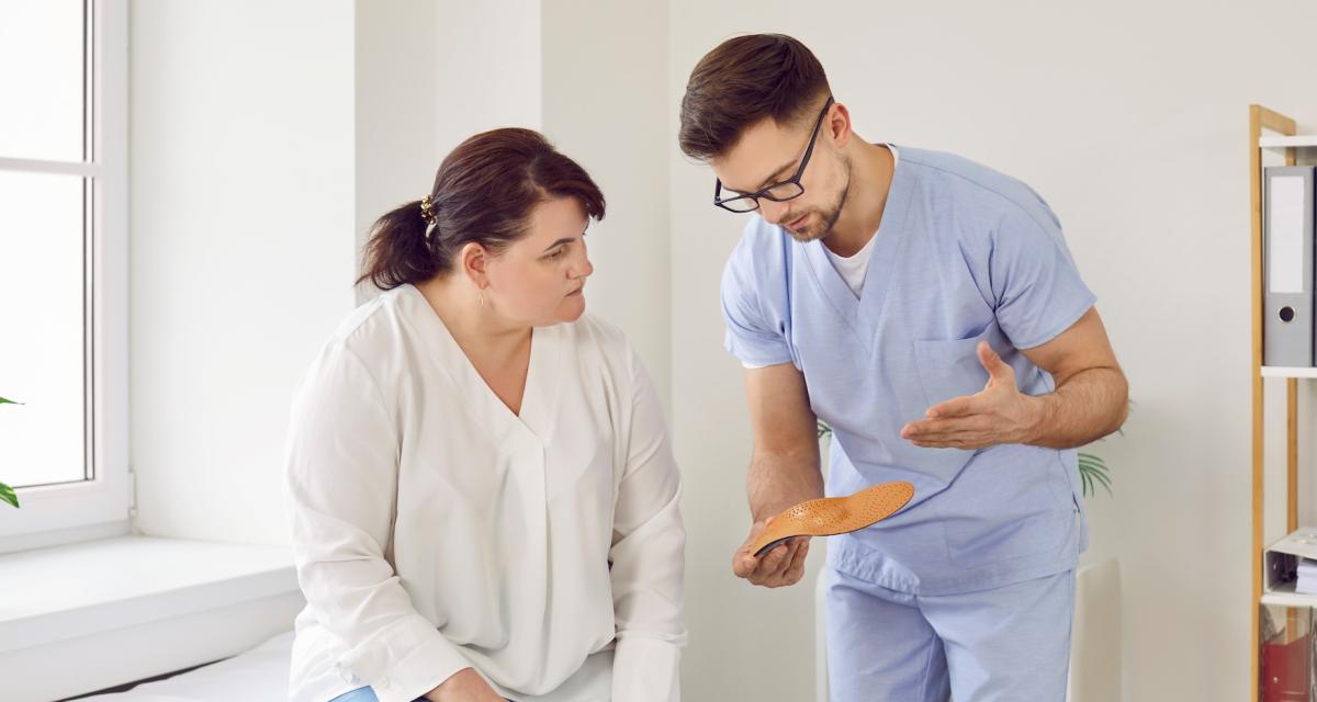 Un podologue présente des semelles orthopédiques à une patiente.