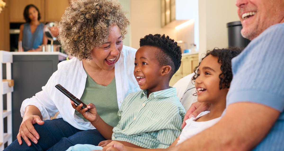 Des grands-parents et leurs petits-enfants regardent un film en famille à la télévision.