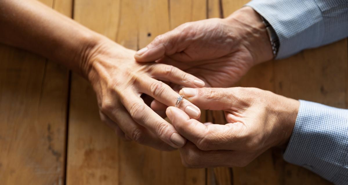 Un homme âgé passe une bague au doigt de sa femme pour leurs 60 ans de mariage.