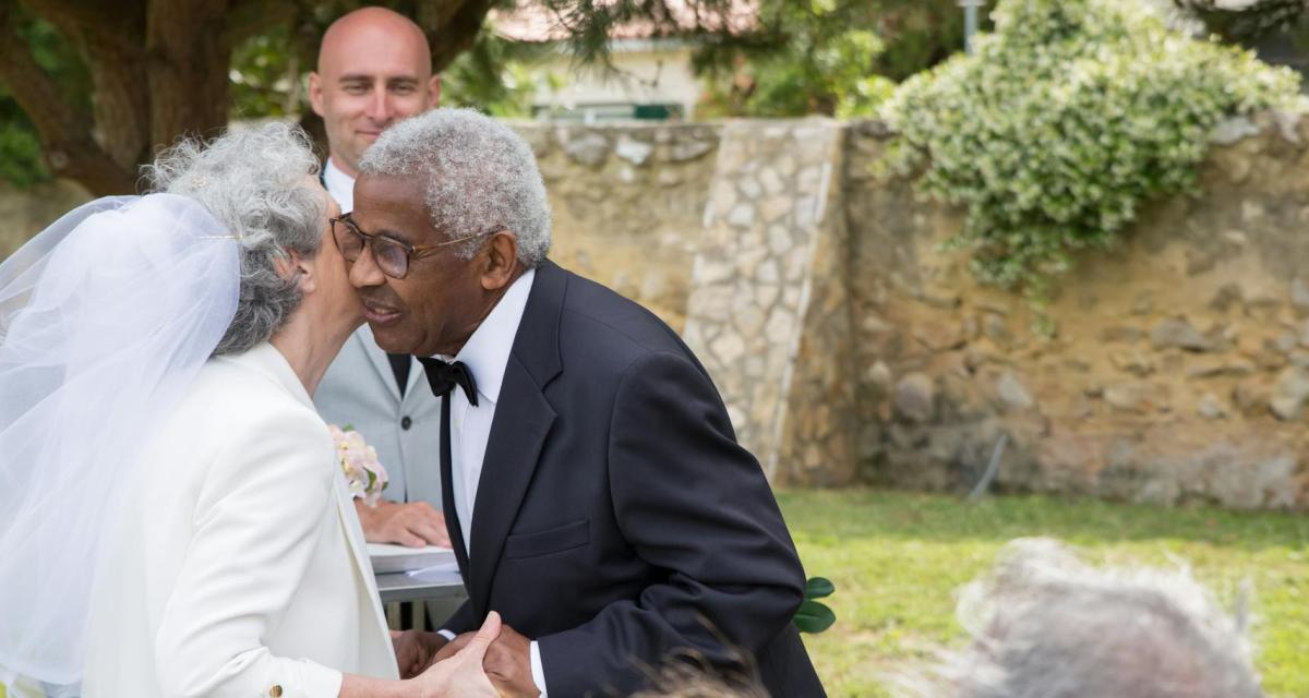 Un couple senior renouvelle ses vœux devant leurs proches avec un maître de cérémonie.