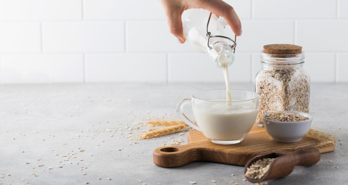 Une personne se sert du lait d'avoine dans une tasse.