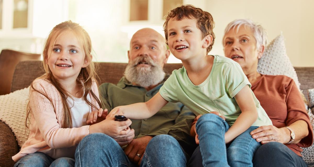 Des grands-parents regardent un film comique avec leurs petits-enfants.