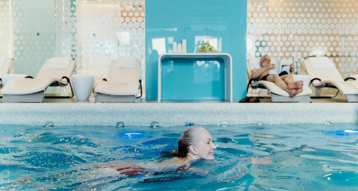 Un couple senior profite de la piscine de leur hôtel pendant leurs vacances.