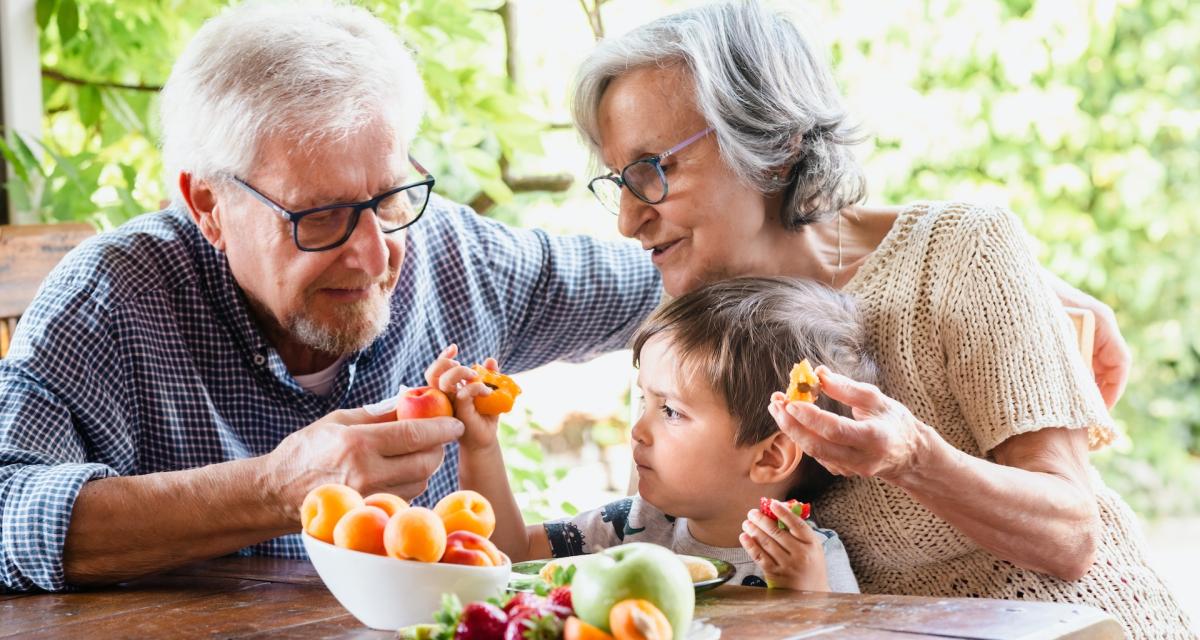 Des grands-parents font découvrir de nouveaux fruits à leur petit-enfant.