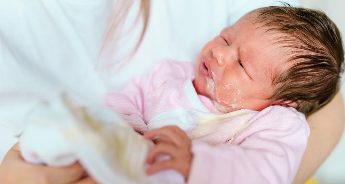 Un bébé vient de régurgiter probablement à cause d'une gastro.