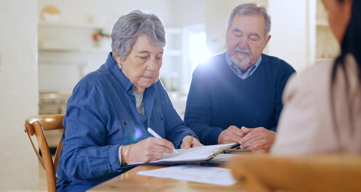 Un couple âgé signe des documents concernant le rachat de leur assurance vie.