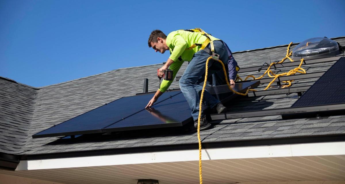 Un technicien installe des panneaux solaires sur un toit.