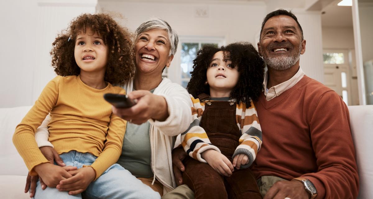 Des grands parents regardent un dessin animé avec leurs petites-filles.