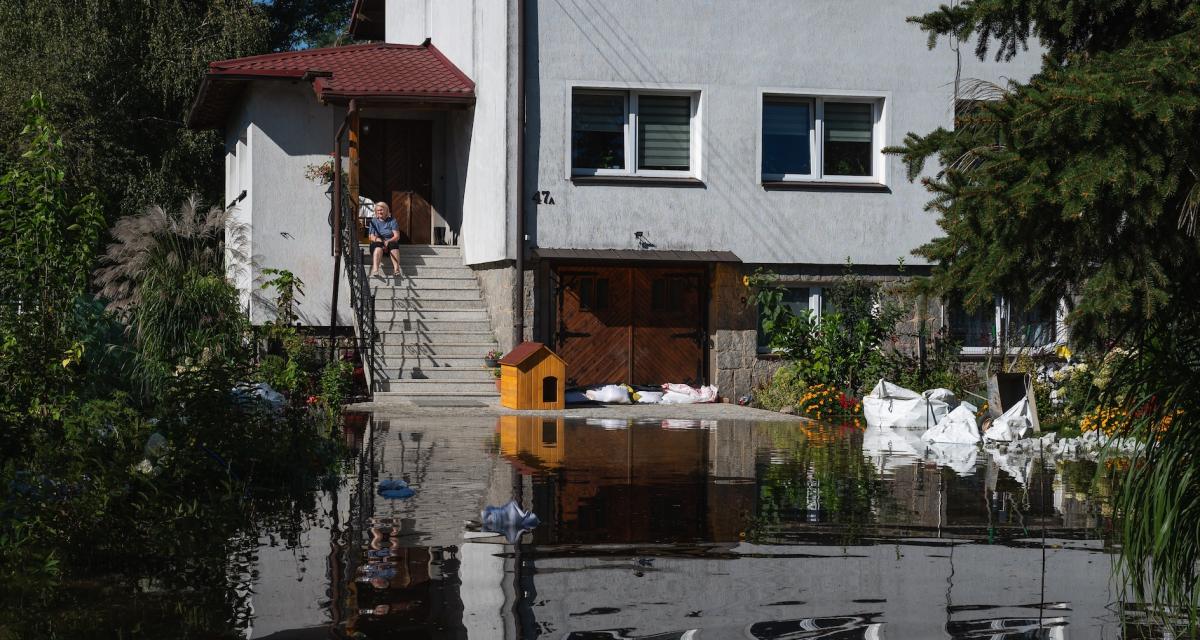 Une femme est assise sur les marches de sa maison inondée.