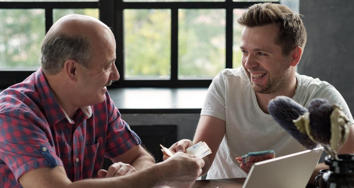 Un père fait un don d'argent à son fils adulte.