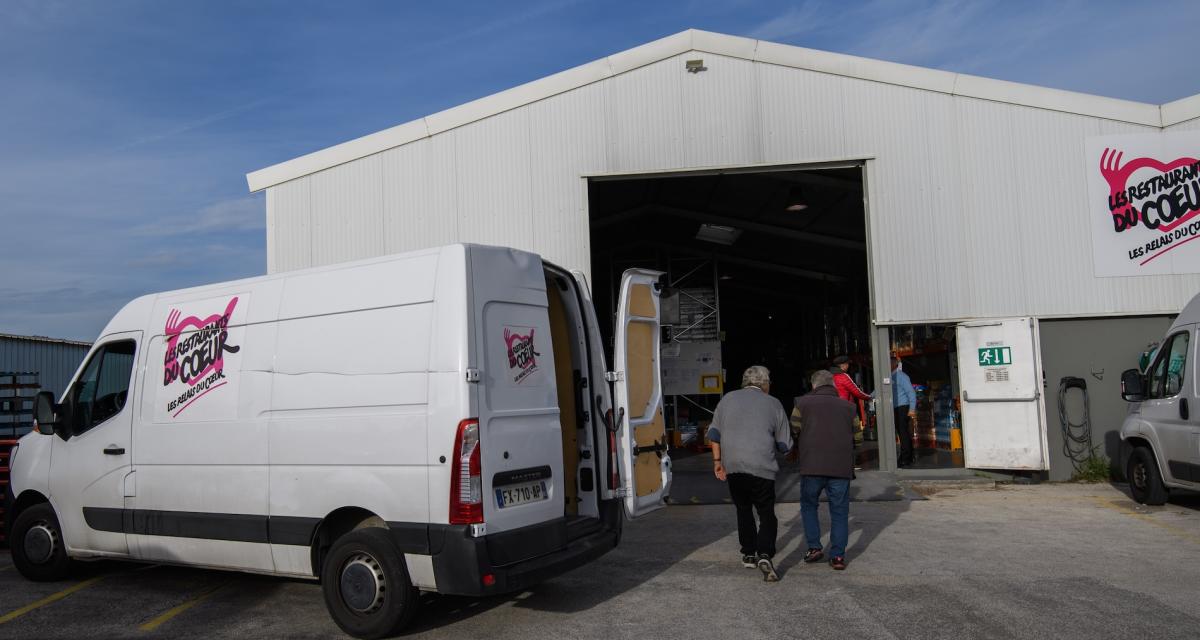 Des bénévoles arrivent à l'entrepôt des Restaurants du Coeur pour remplir les camions de distribution de nourriture.