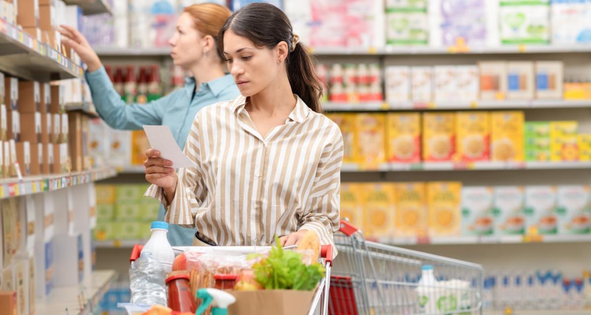 Une femme en train de vérifier sa liste de courses au supermarché.