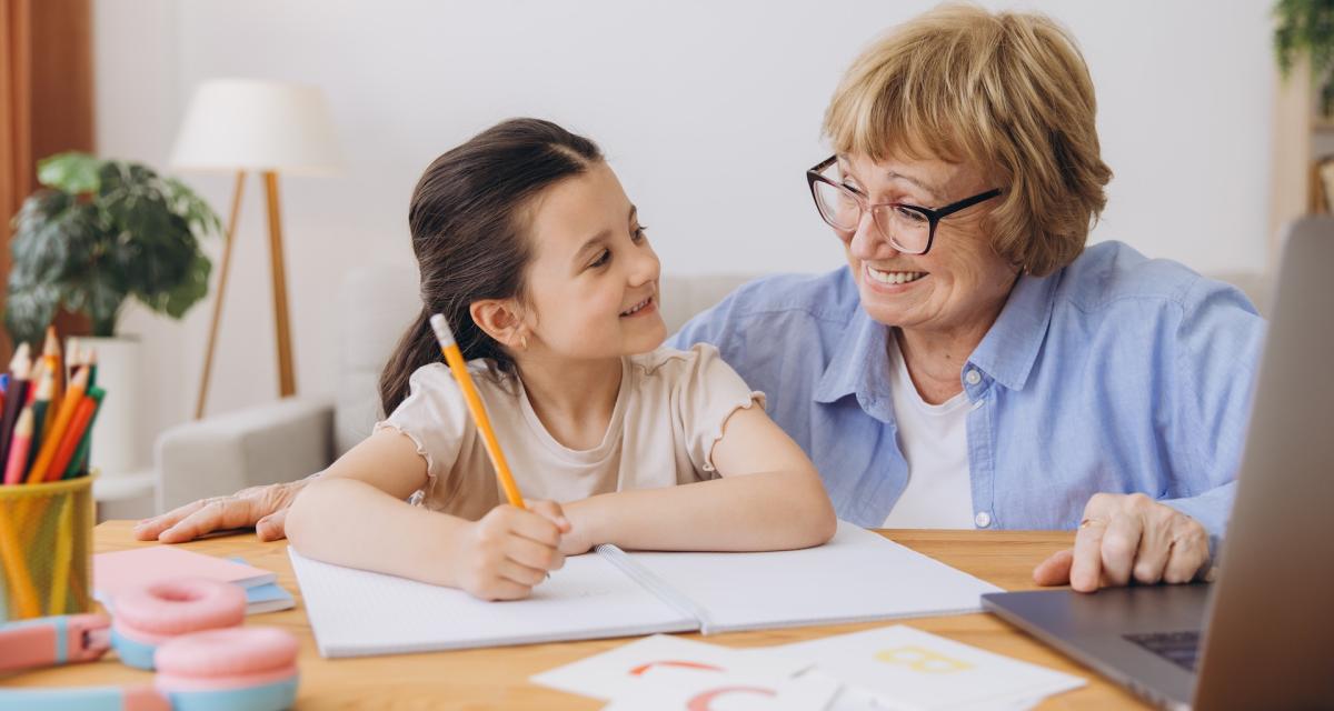 Des grands-parents aident leurs petits-enfants à faire leurs devoirs.