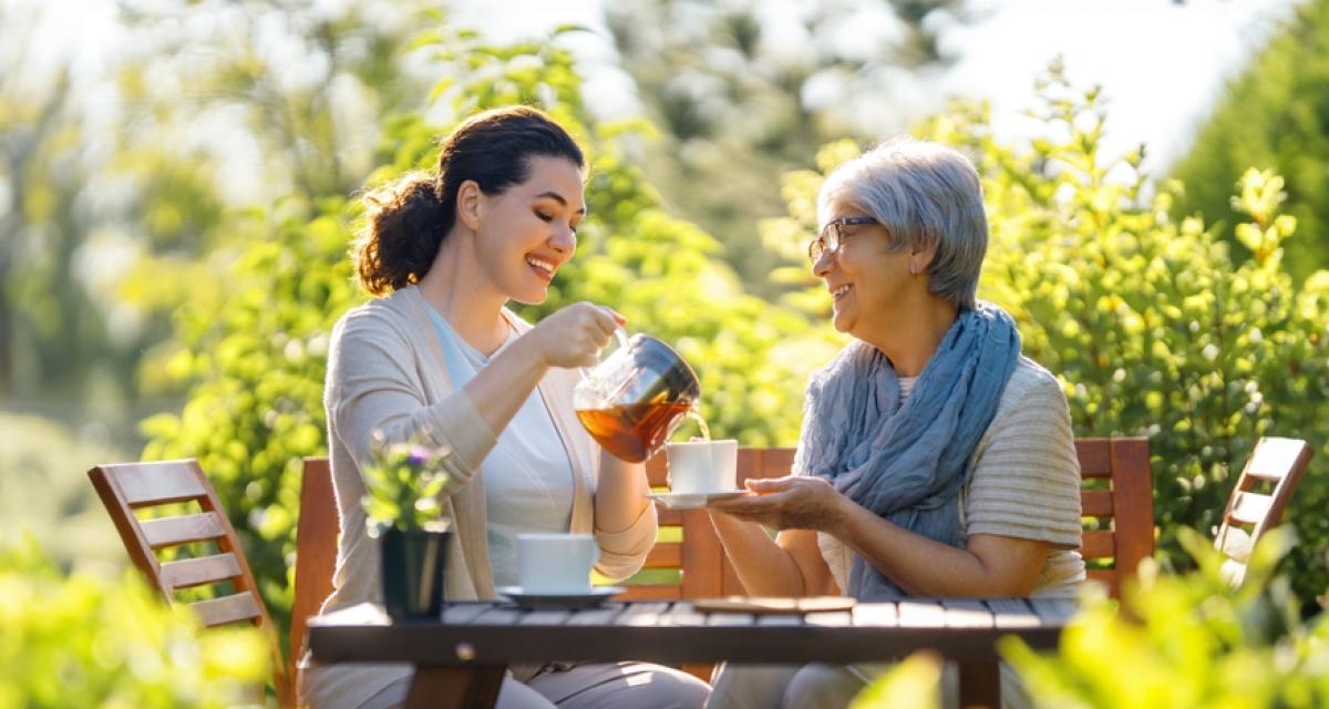 Deux femmes boivent une tasse de rooibos dans un jardin.