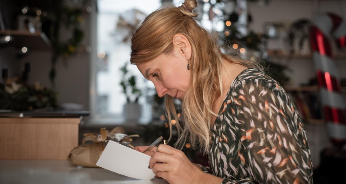 Portrait d'une dame pendant qu'elle écrit une carte de vœux.